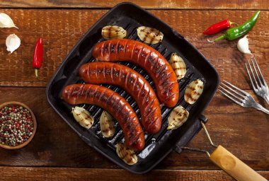 Sebze ve baharat ahşap arka plan üzerinde bir tavada ızgara sosis