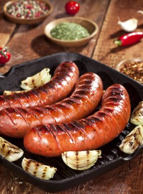 Sebze ve baharat ahşap arka plan üzerinde bir tavada ızgara sosis
