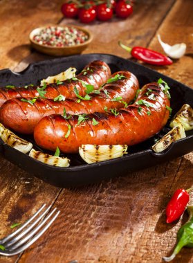 Sebze ve baharat ahşap arka plan üzerinde bir tavada ızgara sosis