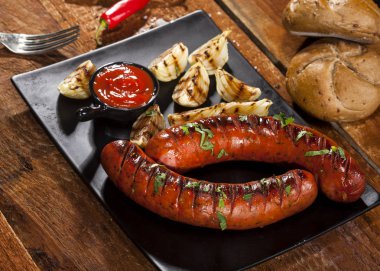 Sebze ve ahşap zemin üzerine bir tabak içinde baharatlar ile ızgara sosis