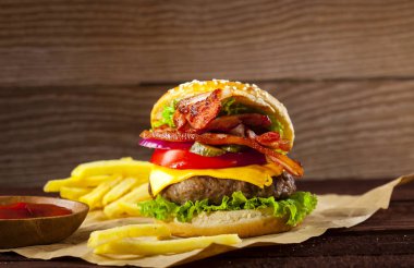 Sığır eti, pastırma, domates, peynir, salatalık, soğan, marul üzerinde kopya alanı ile ahşap arka plan ile taze lezzetli burger