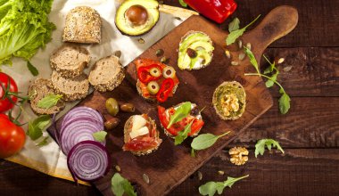 Bir kesme tahtası ve ahşap masa farklı mini sandviç topluluğu. Üstten görünüm.