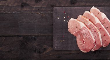 Çiğ et. Baharat kopya alanı ile siyah bir arka plan ile bir kesme tahtası üzerinde ham sığır eti biftek.