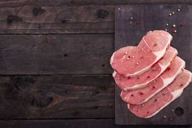 Çiğ et. Baharat kopya alanı ile siyah bir arka plan ile bir kesme tahtası üzerinde ham sığır eti biftek.