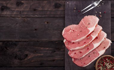 Çiğ et. Baharat kopya alanı ile siyah bir arka plan ile bir kesme tahtası üzerinde ham sığır eti biftek.