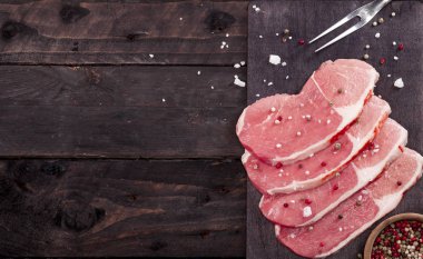 Çiğ et. Baharat kopya alanı ile siyah bir arka plan ile bir kesme tahtası üzerinde ham sığır eti biftek.