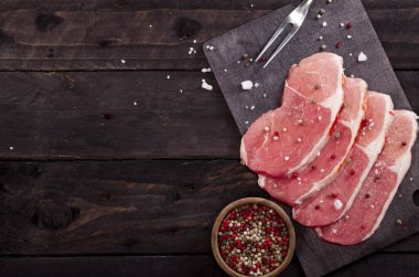 Çiğ et. Baharat kopya alanı ile siyah bir arka plan ile bir kesme tahtası üzerinde ham sığır eti biftek.