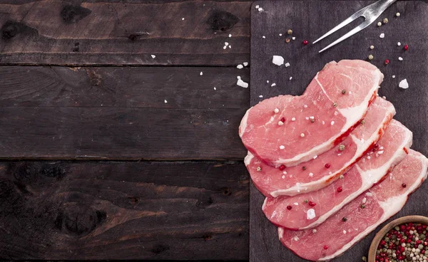 Çiğ et. Baharat kopya alanı ile siyah bir arka plan ile bir kesme tahtası üzerinde ham sığır eti biftek.