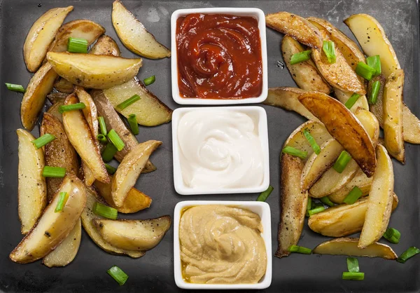 Patates dilimleri chives ve soslar ile pişmiş... Ev yapımı organik sebze vegan vejetaryen patates dilimleri Aperatif yiyecek. Üstten görünüm