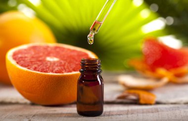 Grapefruit Essential Oil on green leaves background clipart