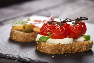 Bruschettas krem peynir, kiraz domates, fesleğen, füme peynir, salam, zeytin ahşap tablo