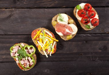 Koyu ahşap masa üzerinde farklı bruschettas kümesi. En iyi görünüm ve kopya alanı.