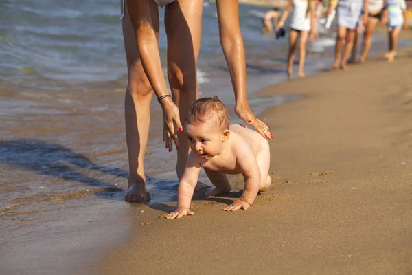 Madre y su bebé jugando en el agua en la playa dorada . —  Fotos de Stock