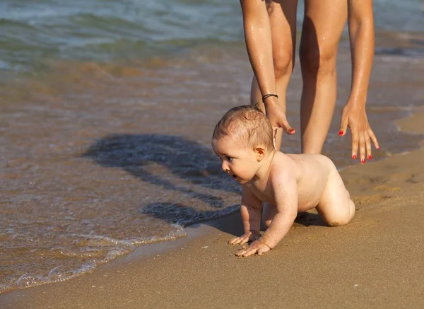 Madre y su bebé jugando en el agua en la playa dorada . —  Fotos de Stock