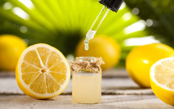 Lemon Essential Oil on green leaves background — Stock Photo, Image