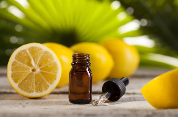 Aceite esencial de limón sobre fondo de hojas verdes — Foto de Stock