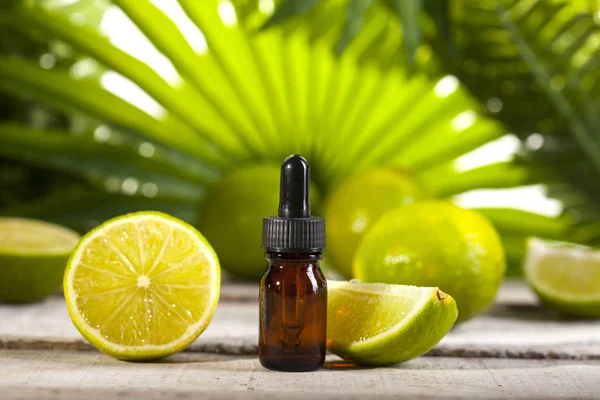Lime eterisk olja på gröna löv bakgrund — Stockfoto