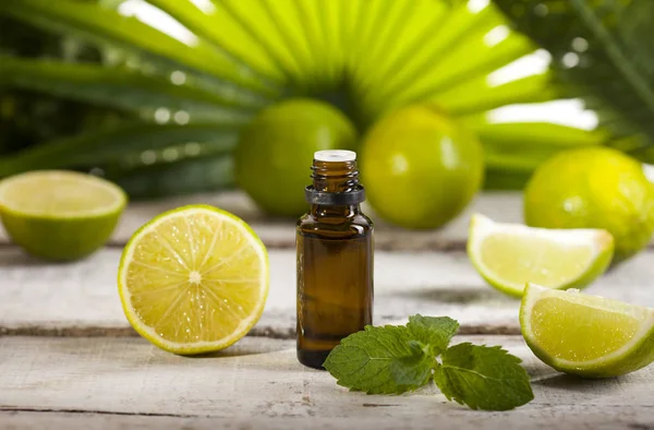 Lime eterisk olja på gröna löv bakgrund — Stockfoto