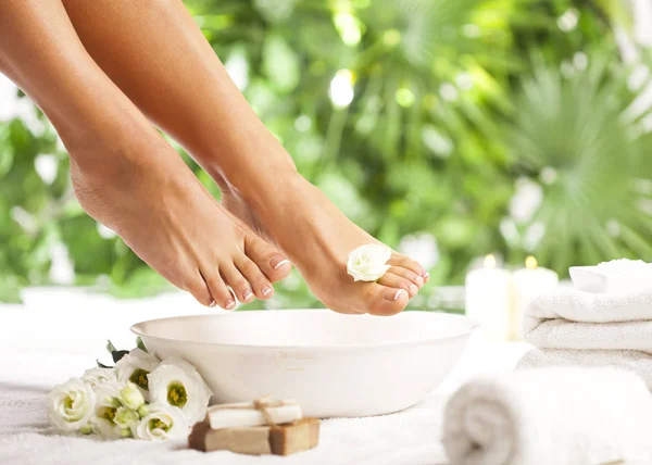 Spa de pie sobre fondo de hojas verdes tropicales — Foto de Stock