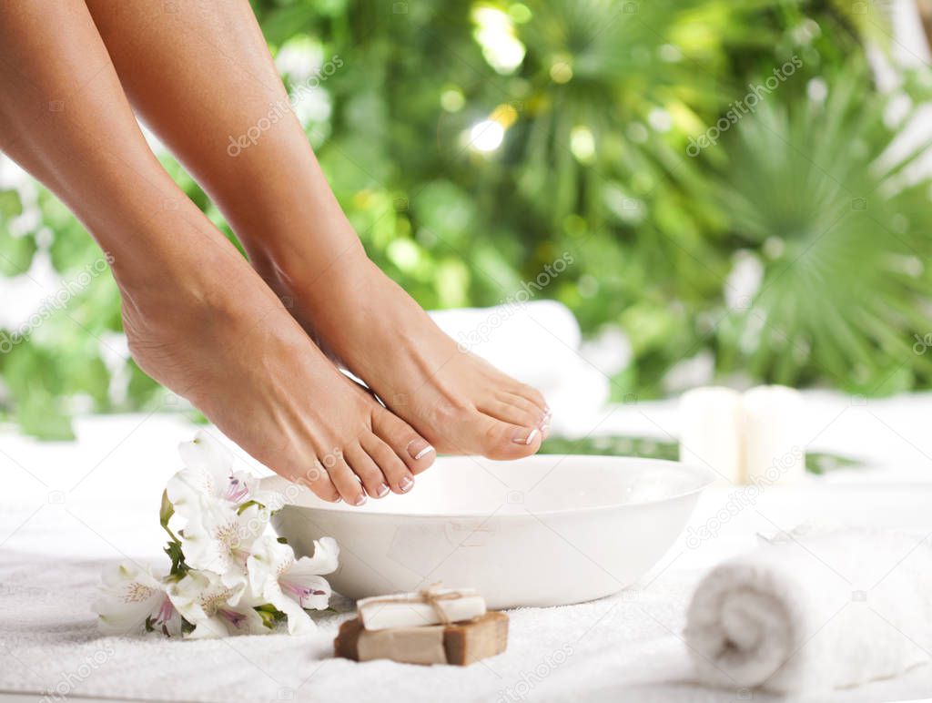 Foot spa on a tropical green leaves background