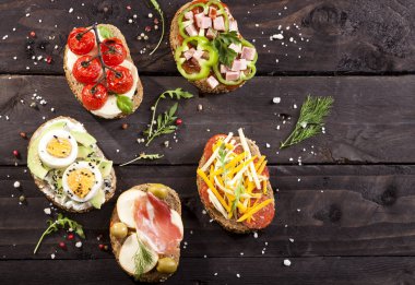 Koyu ahşap masa üzerinde farklı bruschettas kümesi. En iyi görünüm ve kopya alanı.