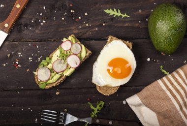 Avokado, rucola susam, tohum, yumurta, ahşap masa üzerinde turp ile iki farklı bruschettas