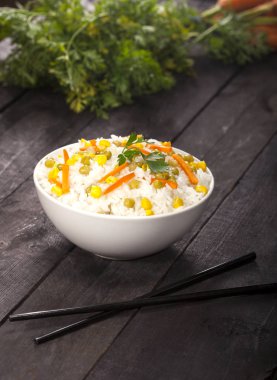 Ahşap siyah arka plan üzerine yemek çubukları ile bir kase sebze ile beyaz pirinç pişmiş.