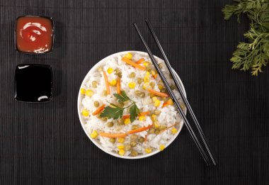 Soslar ve chopsticks ahşap bambu siyah arka plan üzerine bir kase sebze ile beyaz pirinç pişmiş.