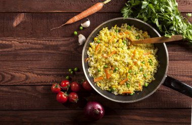 Pişmiş pirinç köri ve sebze bir tavada kahverengi ahşap arka plan üzerinde.