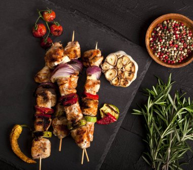 Baharatlar ve sebzeler taş siyah arka plan üzerine ızgara tavuk şiş