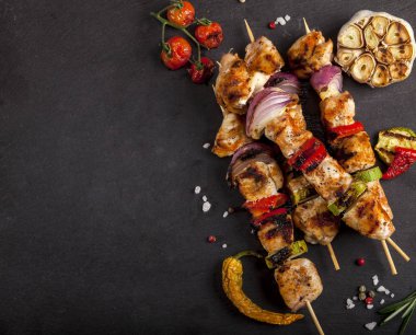 Baharatlar ve sebzeler taş siyah arka plan üzerine ızgara tavuk şiş