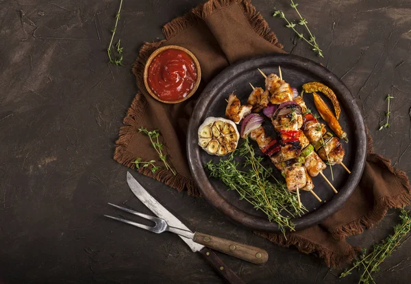 Grillade kycklingspett med kryddor och grönsaker i en kastrull på mörk bakgrund — Stockfoto