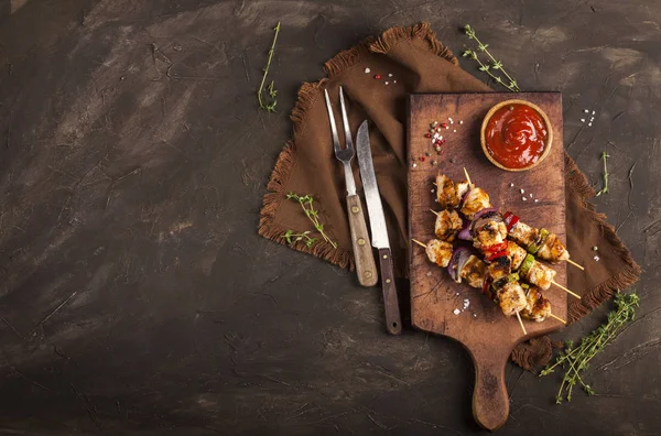 Grillade kycklingspett med kryddor och grönsaker på skärbräda och mörk bakgrund — Stockfoto