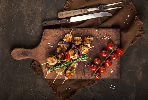 Grillade kycklingspett med kryddor och grönsaker på skärbräda och mörk bakgrund — Stockfoto