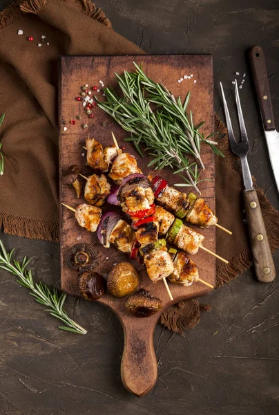 Grillade kycklingspett med kryddor och grönsaker på skärbräda och mörk bakgrund — Stockfoto