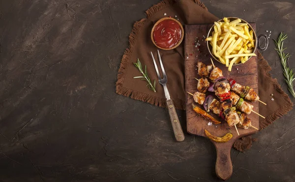 Grillade kycklingspett med kryddor, grönsaker och pommes på skärbräda och mörk bakgrund — Stockfoto