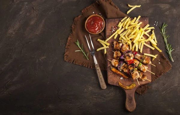 Grillade kycklingspett med kryddor, grönsaker och pommes på skärbräda och mörk bakgrund — Stockfoto