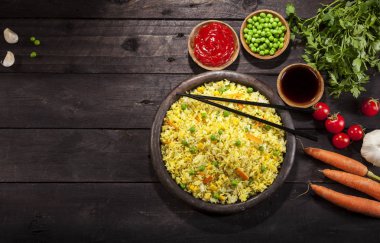 Pişmiş pirinç köri ve ahşap siyah arka plan üzerine yemek çubukları ile bir tavada sebze ile.