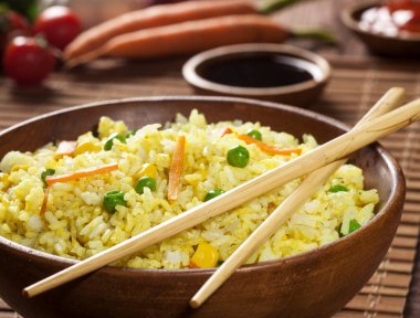 Odun kahverengi bambu arka planda soslar ve Chopsticks ile bir kase köri ve sebzeler ile pişmiş pirinç.