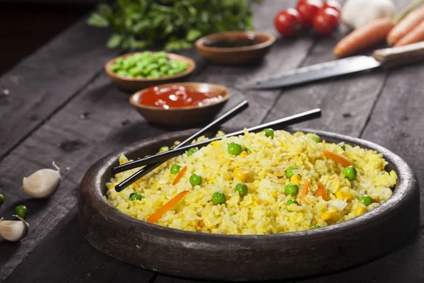 Gekochter Reis mit Curry und Gemüse in einer Pfanne mit Essstäbchen auf schwarzem Hintergrund. — Stockfoto