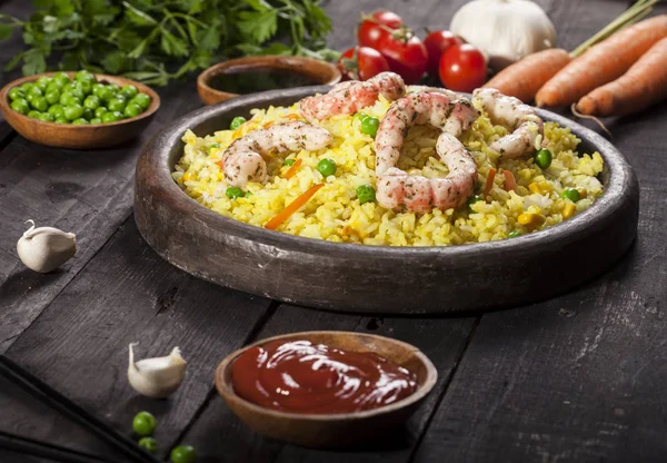 Gekookte rijst met garnalen, curry en groenten in een schotel op het hout zwarte bamboe achtergrond. — Stockfoto