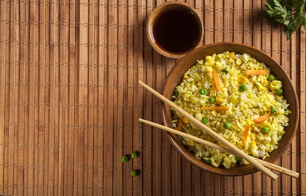 Gekochter Reis mit Curry und Gemüse in einer Schüssel mit Soßen und Essstäbchen auf dem Holz braunen Bambus Hintergrund. — Stockfoto