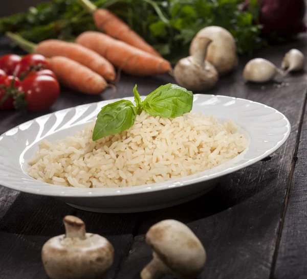 Gekochter weißer Reis in einem Teller auf schwarzem Holzhintergrund. — Stockfoto