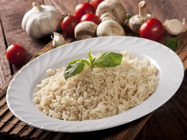 Cooked white rice in a plate on wooden background.