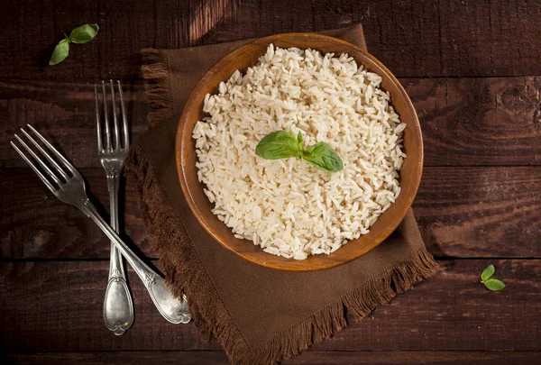 Cooked white rice in a bowl on wooden background.