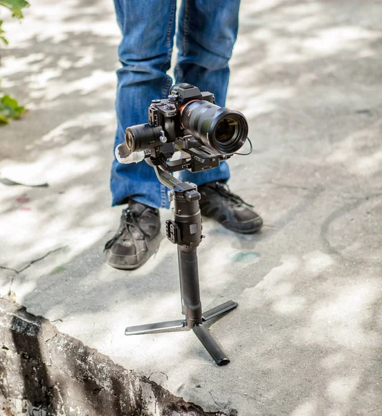 O tipo do vídeo filma vídeo com uma câmara e um estabilizador de gimbal com uma mão. A câmera fica no chão . — Fotografia de Stock