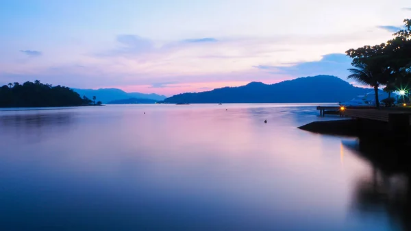Hareketsiz okyanusta refleksleri ile güzel mor günbatımı - Arka planda Ada ve tepeler 
