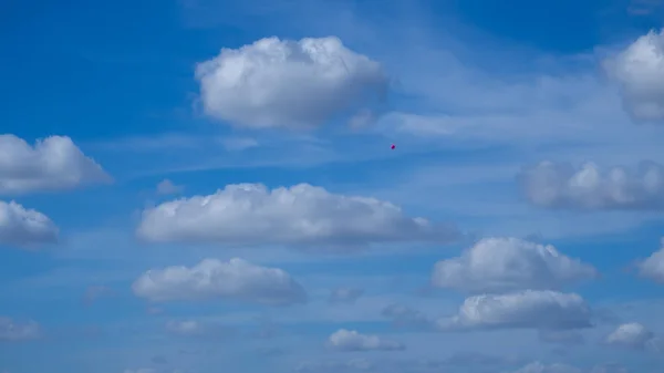 Mavi gökyüzü ve küçük pembe balonu olan güzel bulutlar.