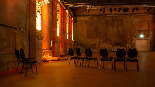 Leipzig, Almanya - 14.09.2019: Sanayi salonunda sergi, sanat müzesindeki ziyaretçiler için hazırlanmış sandalyelerle sıcak renklerle aydınlatıldı (Kunstkraftwerk)