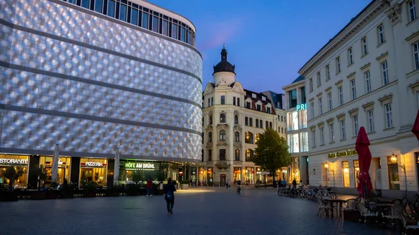 Leipzig, Almanya - 14.09.2019: Leipzig şehrinde geceleri güzel ışıklı dükkanlar ve etrafta yürüyen insanlarla alışveriş alanı